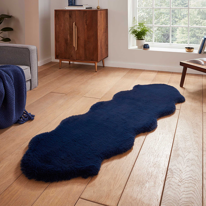 image of long navy blue sheepskin rug with wavy edges on wooden flooring in front of window with natural light streaming through