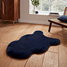 image of short navy blue sheepskin rug with wavy edges on wooden flooring in front of window with natural light streaming through