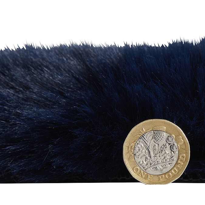 side-on image of faux sheepskin rug with pound coin stood up next to it to show rug as double the height of coin