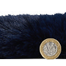 side-on image of faux sheepskin rug with pound coin stood up next to it to show rug as double the height of coin