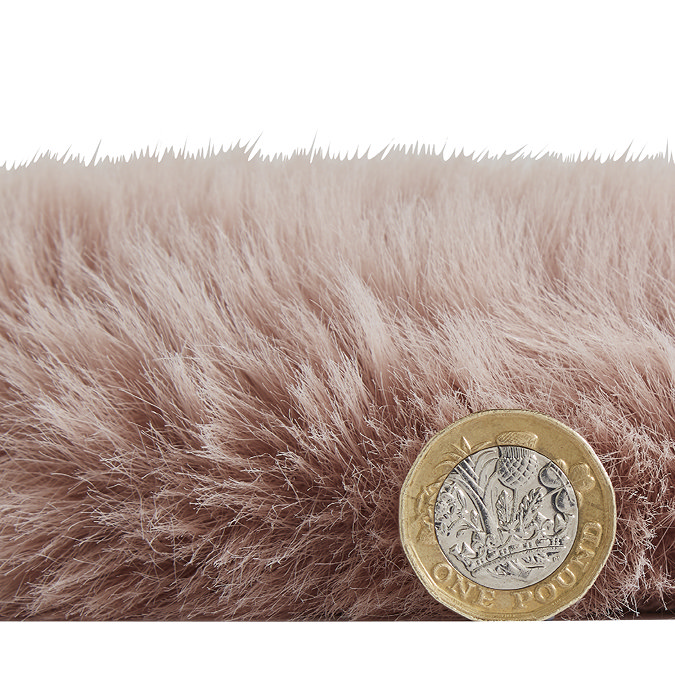 side-on image of faux sheepskin rug with pound coin stood up next to it to show rug as double the height of coin