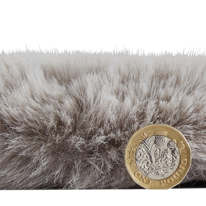 side-on image of faux sheepskin rug with pound coin stood up next to it to show rug as double the height of coin