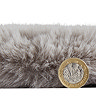 side-on image of faux sheepskin rug with pound coin stood up next to it to show rug as double the height of coin