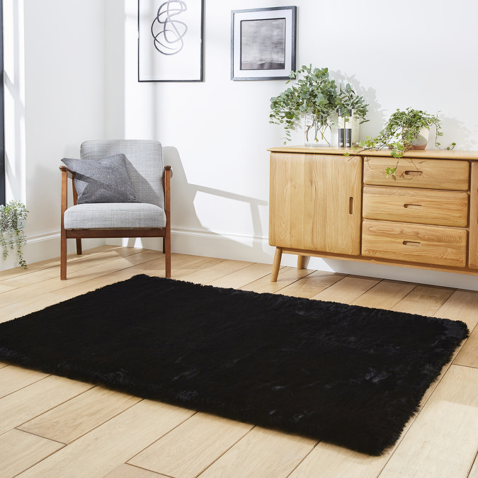 angled image of black soft rectangle rug on wooden floor of loft apartment