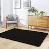 angled image of black soft rectangle rug on wooden floor of loft apartment