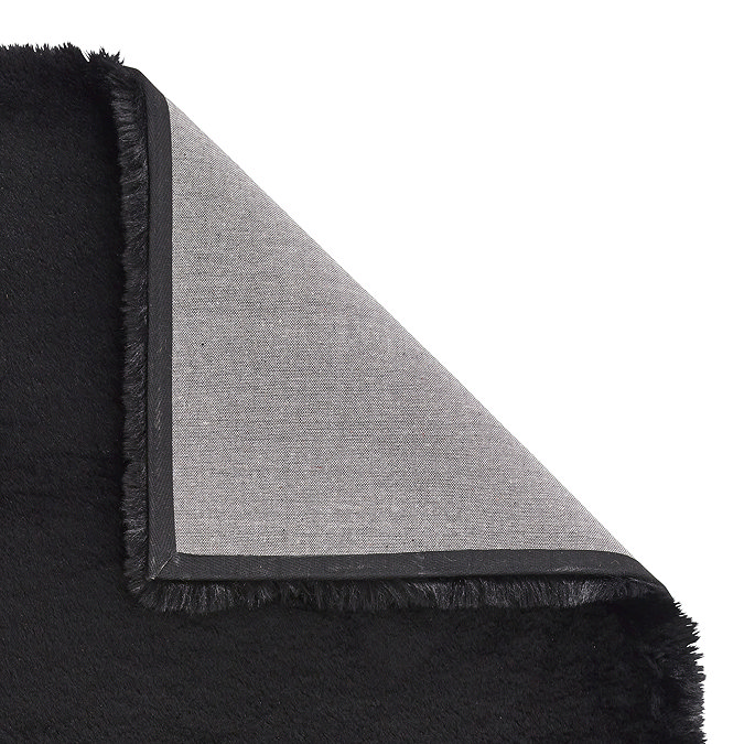 image of black soft rug with corner folded over to show floor-facing material underneath