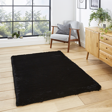 angled image of black soft rectangle rug on wooden floor of loft apartment