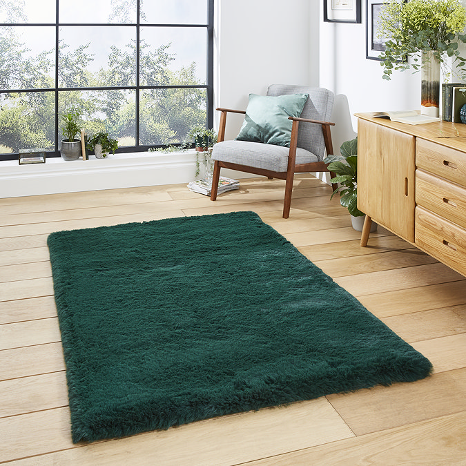 image of emerald green soft rug on light wooden flooring of modern loft apartment in front of wooden sideboard