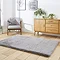 angled image of soft grey rectangle rug on wooden flooring