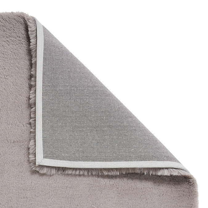 image of soft grey rug folded over in the corner to show floor-facing material underneath