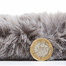 side on image of soft rug lying flat with pound coin stood up next to it to show rug as double the height of the coin