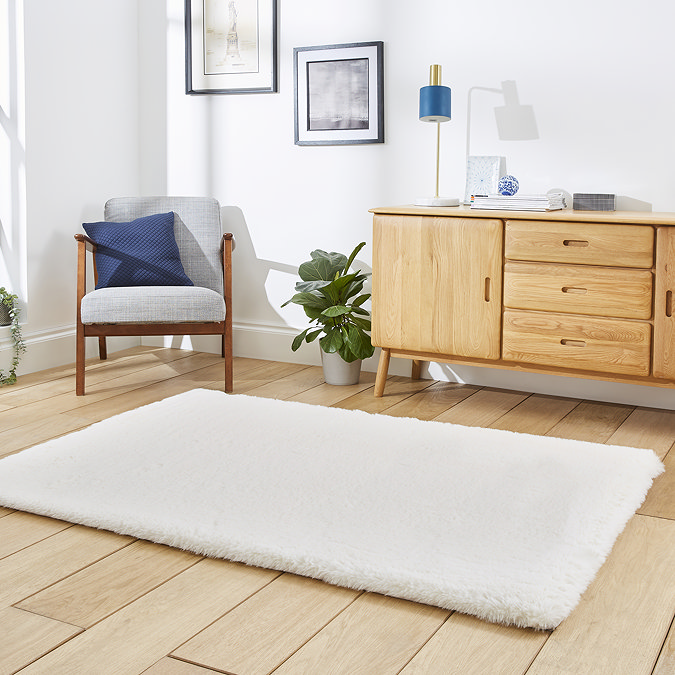 angled image of soft ivory rug on light wooden flooring in front of sideboard