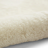 close up image of soft ivory rug rolled up on one end