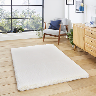 image of ivory rug on light wooden floor in front of wooden sideboard