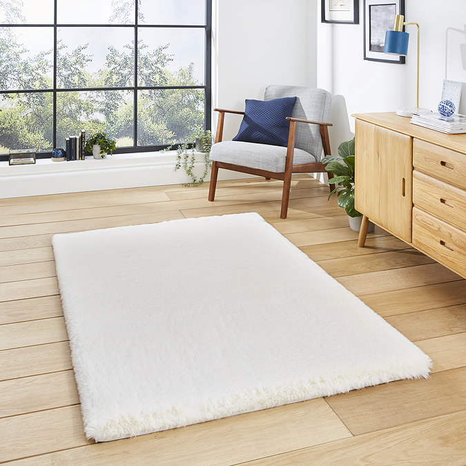 image of ivory rug on light wooden floor in front of wooden sideboard