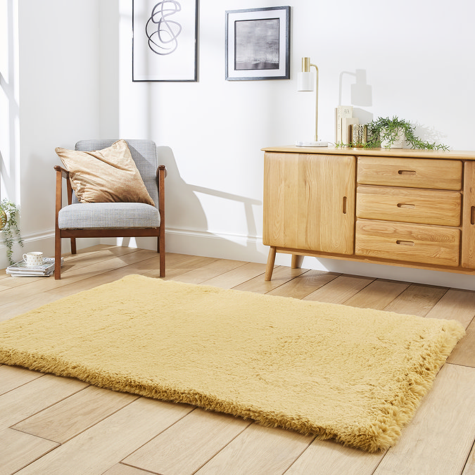 image of mustard yellow soft rug on light wooden flooring in front of sideboard