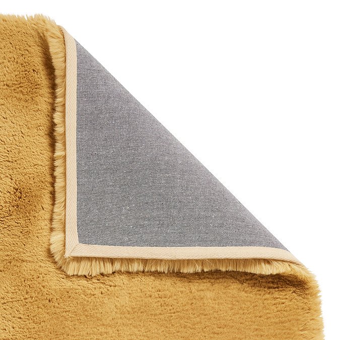 image of soft mustard yellow rug with corner folded over to reveal floor-facing material underneath