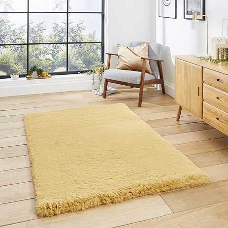 image of mustard yellow soft rectangle rug on light wooden flooring in front of wide open window in modern loft apartment