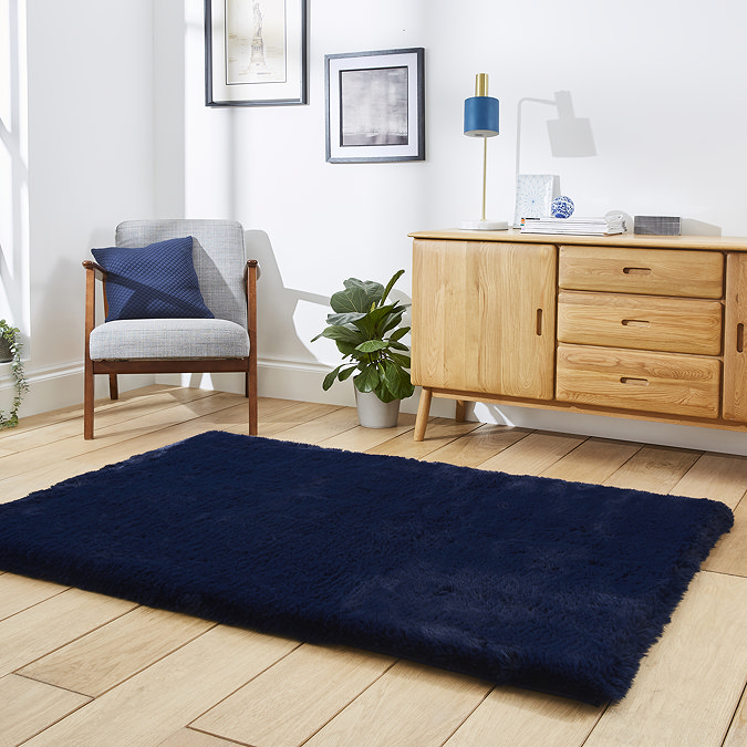 angled image of navy blue soft rug on wooden floor in front of sideboard