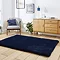 angled image of navy blue soft rug on wooden floor in front of sideboard