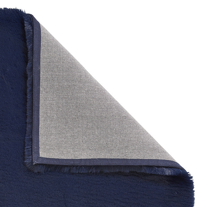 image of navy blue soft rug with corner folded over to show floor-facing material underneath
