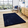 image of navy blue soft rectangle rug on light wooden flooring of modern loft apartment in front of wide window