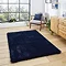 image of navy blue soft rectangle rug on light wooden flooring of modern loft apartment in front of wide window