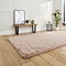 angled image of rose pink soft rug on wooden flooring in front of cream wall and modern dressing table bench with mirror