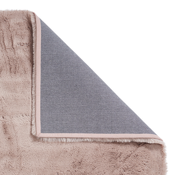 image of rose pink rug folded over in the corner to show floor-facing material underneath