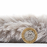 side on image of soft silver fluffy rug with pound coin stood next to it to show rug as double the height of coin