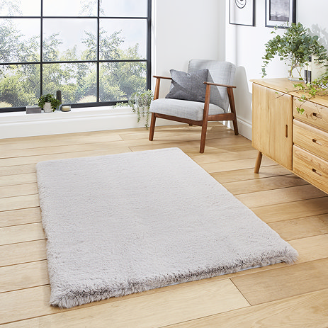 image of soft silver rectangle rug on light wooden flooring of modern loft apartment in front of wide window