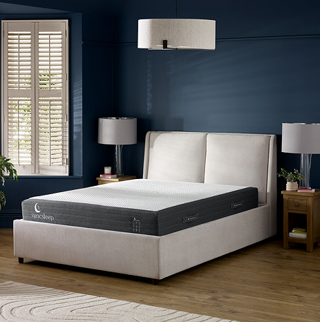 image of deep grey mattress on double bed in front of dark blue bedroom wall