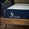 close up image on front left corner of navy blue mattress in a dark wood bedframe, with syncsleep crescent moon logo embroidered in white on it