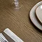 close up image of dark oak wood grain of dining table with cutlery and neutral crockery