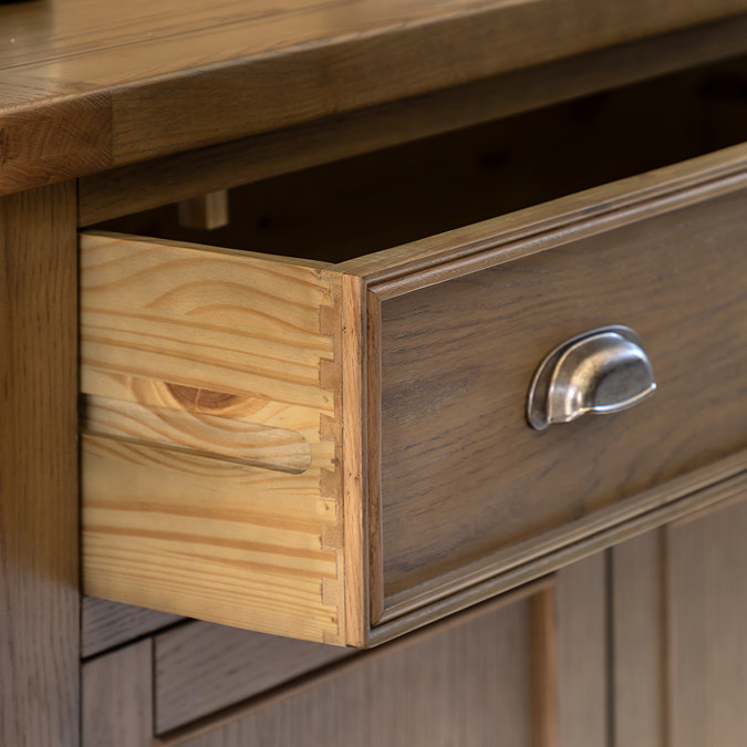 close up on wooden drawer of dark oak sideboard, pulled out to suggest storage space inside