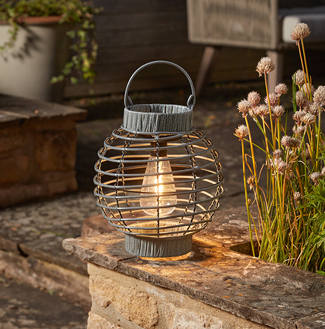 image of grey rattan round lantern on stone terrace