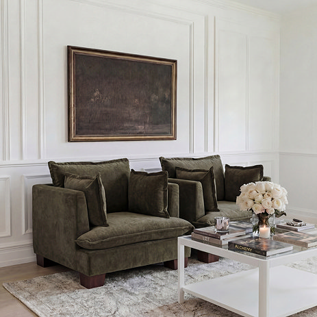 image of two olive green chenille armchairs against panelled wall with painting