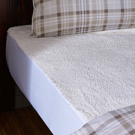 cream fluffy underblanket, over the top of a mattress and revealed by a checked duvet pulled back.