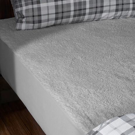 grey sherpa underblanket on top of a mattress, with duvet cover pulled back to reveal it