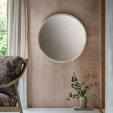 close up on middle section of rounded wall mirror, focus on lime wash of frame and smooth glass
