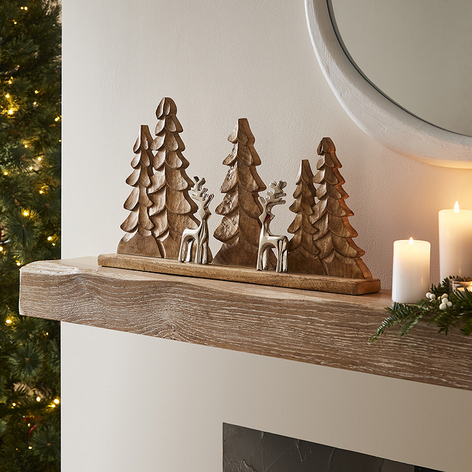wood trees and metal reindeer decoration, displayed on a light oak mantlepiece