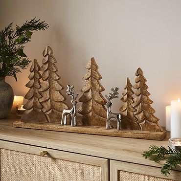 wood trees and metal reindeer decoration, displayed on a light oak mantlepiece
