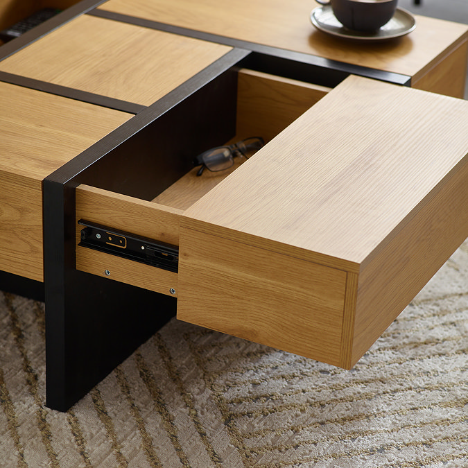 close up on corner of square cubed coffee table with one corner drawer pulled out to reveal ample storage space inside