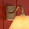 close up on antique brass curved arm of conical fabric wall light