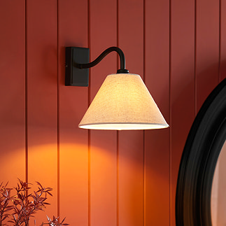 image of conical wall light with fabric shade and curved matt black arm against a brick orange panelled wall
