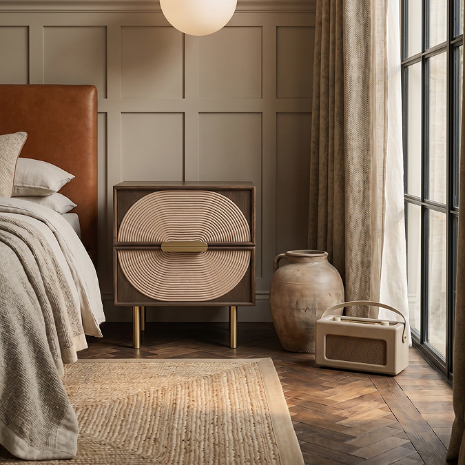 wide image of dark oak bedside table with circular rope design and gold legs, next to brown leather headboard with jute rug in front