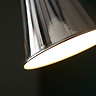 close up image of base of conical floor lamp shade with white light shining out of it