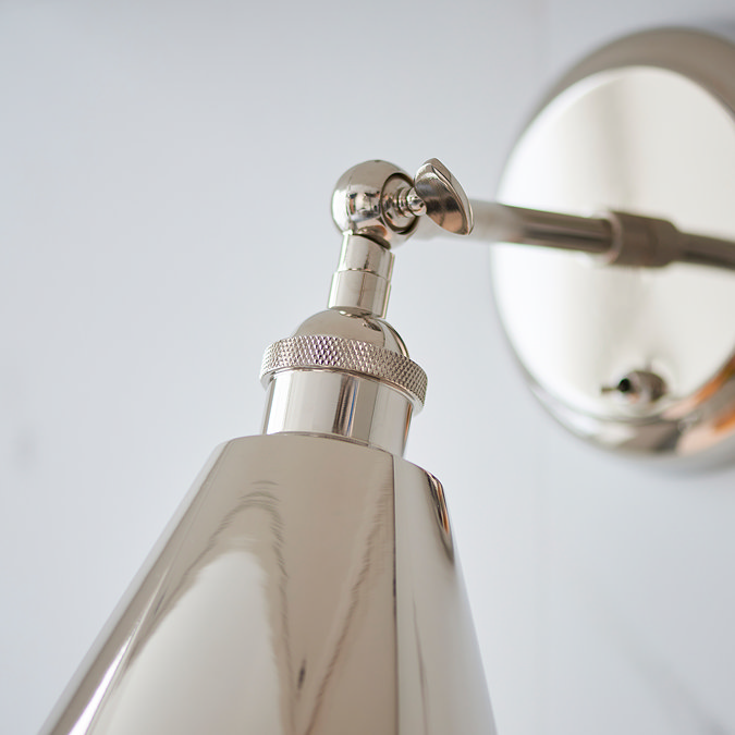 close up image of where arm fixture of nickel coloured wall light meets the conical shade