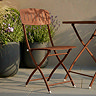 close up image of dark orange-pink bistro set on patio