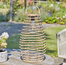 image taken during the day of tall rattan garden lantern on a wooden table